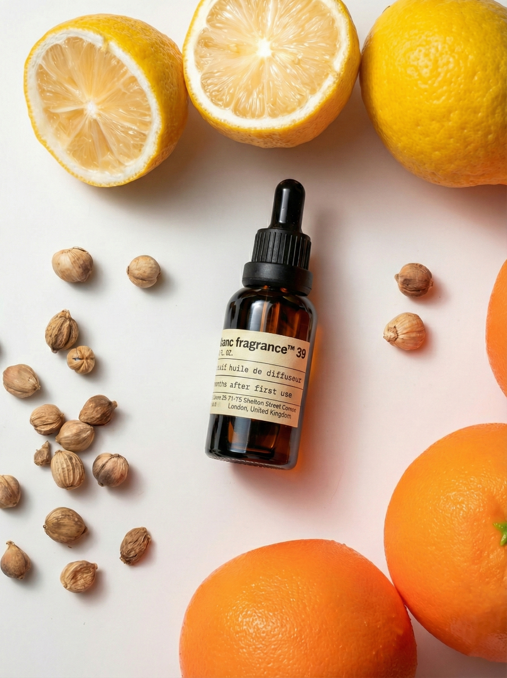 Charabanc Fragrance NO.39 Citrus Delight essential oil bottle styled with fresh halved lemons, oranges, and cardamom pods, evoking a Mediterranean summer.