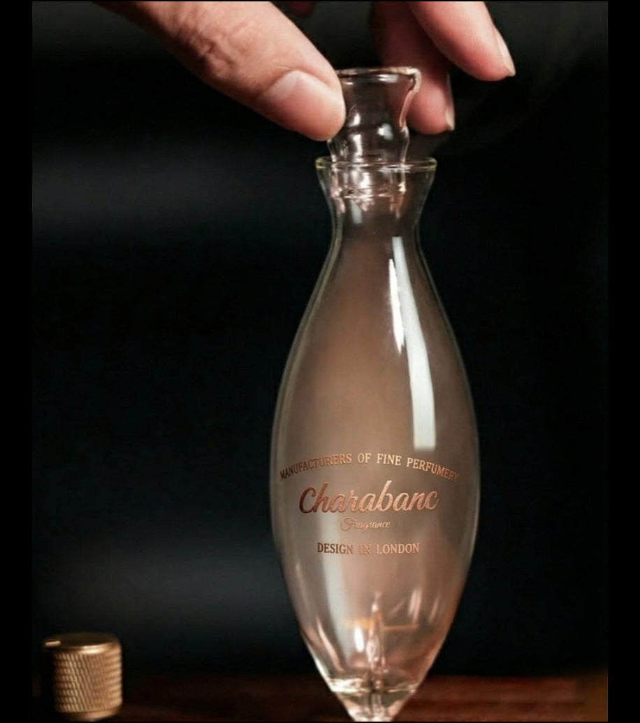 "A detailed close-up view focusing on the artisanal hand-blown glass nebulizer of the Charabanc waterless diffuser. A dense, swirling plume of pure aromatic vapor is actively rising from the clear glass chamber against a warm, blurred background, showcasing the powerful diffusion performance."
